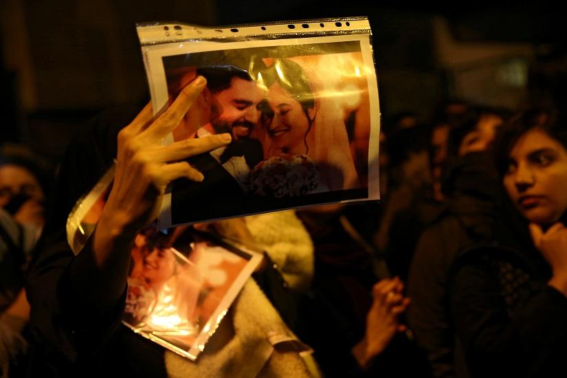 FILE PHOTO: A woman holds a picture of newlyweds, victims of the crash of the Boeing 737-800 plane, flight PS 752, as people gather to show their sympathy in Tehran, Iran Jan 11, 2020. Nazanin Tabatabaee/WANA (West Asia News Agency) via REUTERS