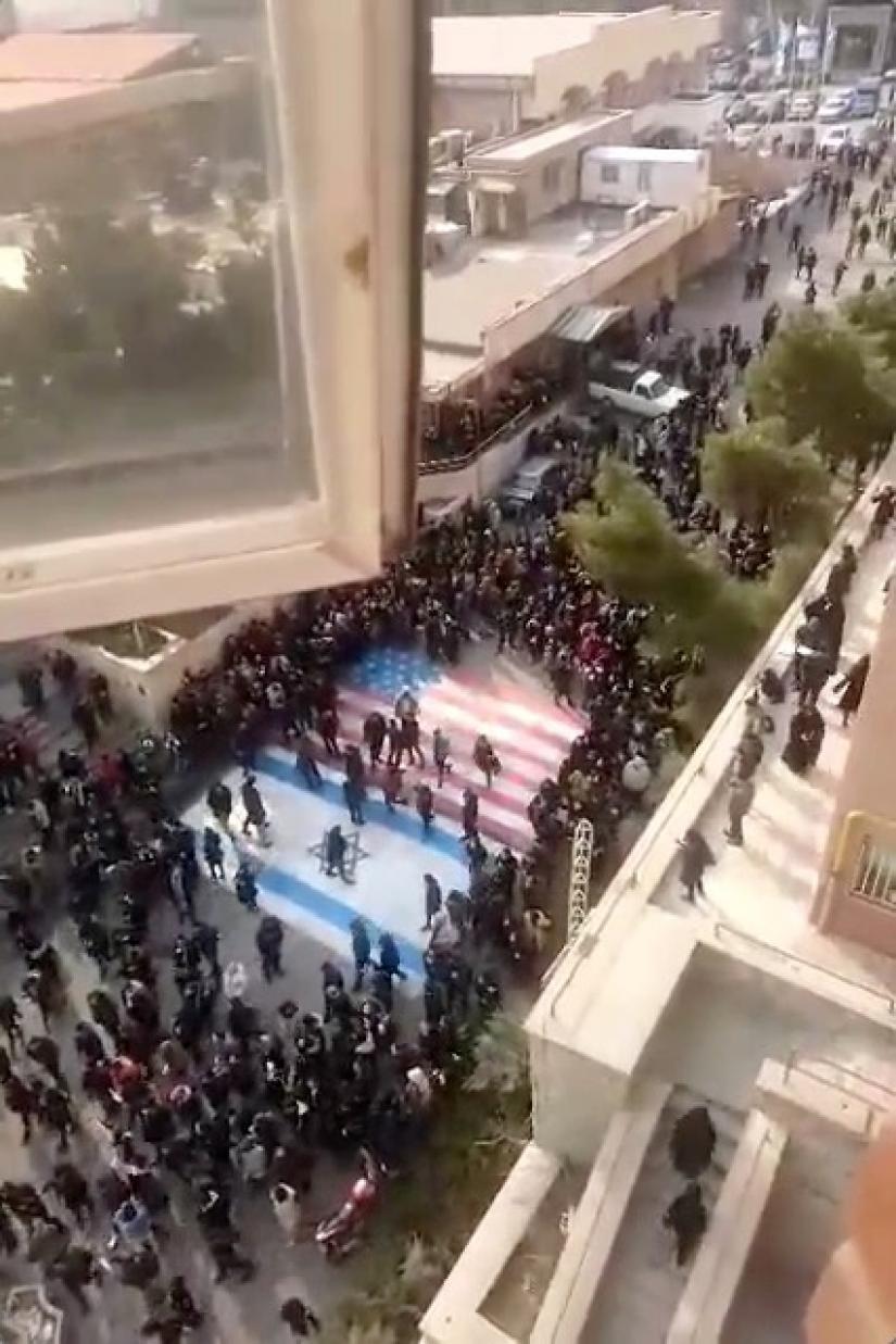 Several people walk on U.S. and Israeli flags while others avoid stepping on the flags by walking around them, at the Shahid Beheshti University in Tehran, Iran January 12, 2020, in this image obtained from a social media video. Courtesy of @MAMLEKATE/Social Media via REUTERS.