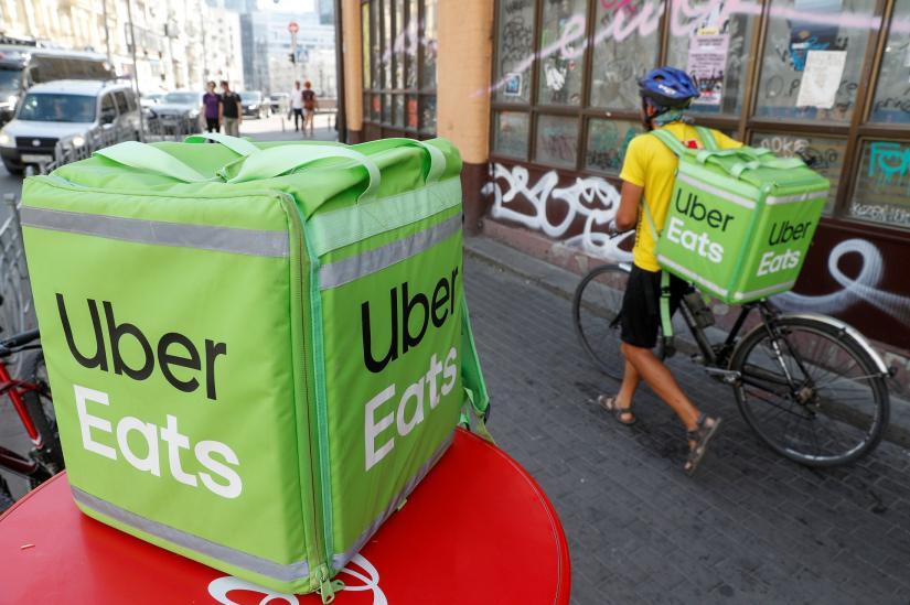 FILE PHOTO: An Uber Eats food delivery courier pulls a bicycle in central Kiev, Ukraine September 9, 2019. REUTERS
