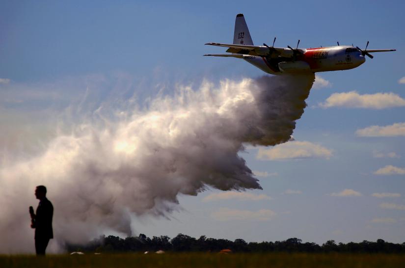 FILE PHOTO: A television reporter stands in front of a Large Air Tanker (LAT) C-130 Hercules as it drops a load of around 15,000 litres during a display by the Rural Fire Service ahead of the bushfire season at RAAF Base Richmond Sydney, Australia, September 1, 2017. REUTERS
