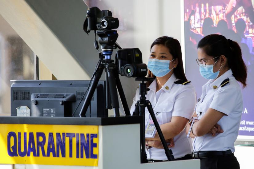 Airport personnel monitor a thermal scanner as passengers arrive at the Ninoy Aquino International Airport in Pasay, Philippines, January 23, 2020. REUTERS