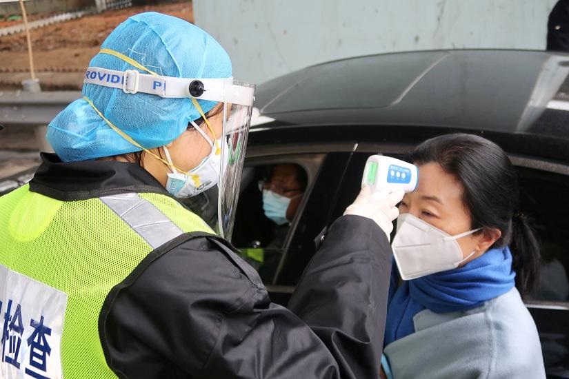 A security officer in a protective mask checks the temperature of a passenger following the outbreak of a new coronavirus, at an expressway toll station on the eve of the Chinese Lunar New Year celebrations, in Xianning, a city bordering Wuhan to the north, Hubei province, China Jan 24, 2020. REUTERS