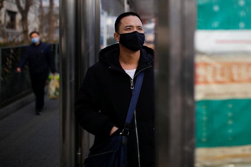A man wearing a face mask looks at a board at a bus stop, as the country is hit by an outbreak of the new coronavirus, in Beijing, China January 27, 2020. REUTERS