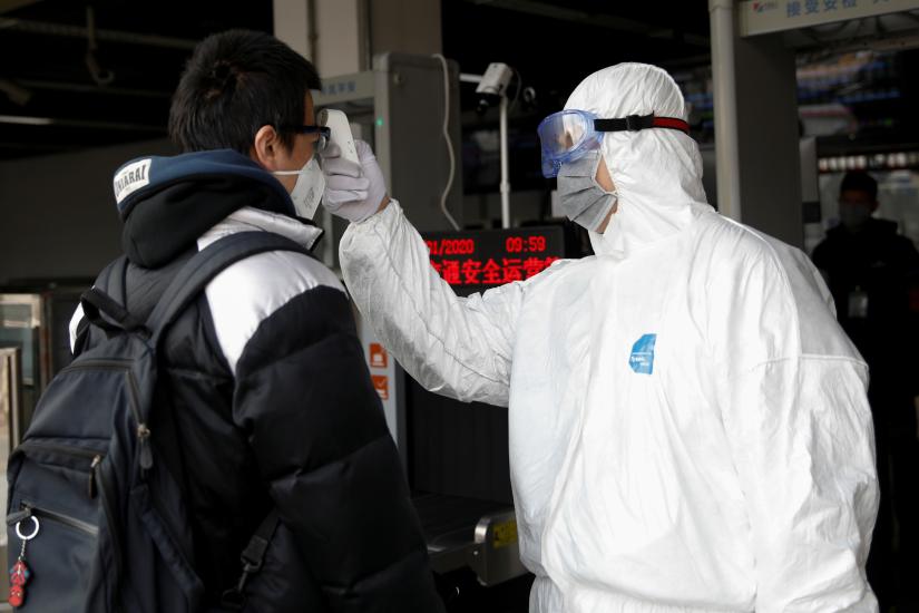 A worker in protective suit uses a thermometer to check the temperature of a man while he enters the Xizhimen subway station, as the country is hit by an outbreak of the new coronavirus, in Beijing, China January 27, 2020. REUTERS