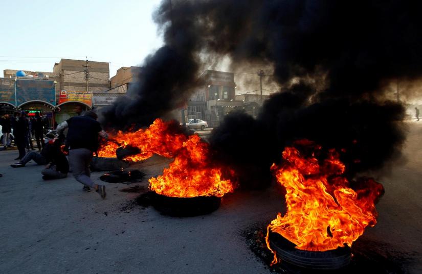 Iraqi demonstrators burn tires to block a road during ongoing anti-government protests in Najaf, Iraq Jan 27, 2020. REUTERS