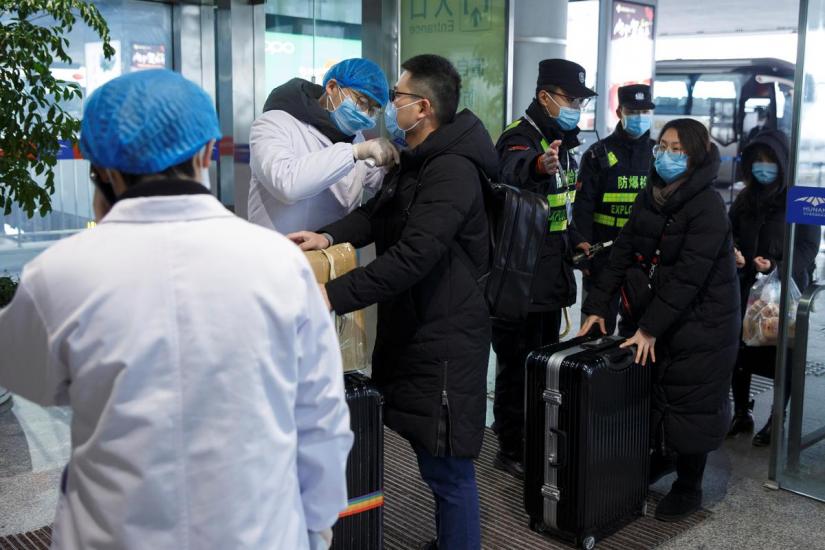 A medical official takes the body temperature of a man at the departure hall of the airport in Changsha, Hunan Province, as the country is hit by an outbreak of a new coronavirus, China, Jan 27, 2020. REUTERS