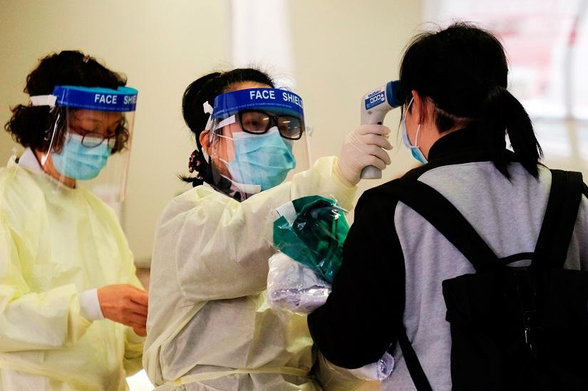 A medical worker takes the temperature of a woman in the reception of Queen Elizabeth Hospital, following the outbreak of a new coronavirus, in Hong Kong, China Feb 3, 2020. REUTERS