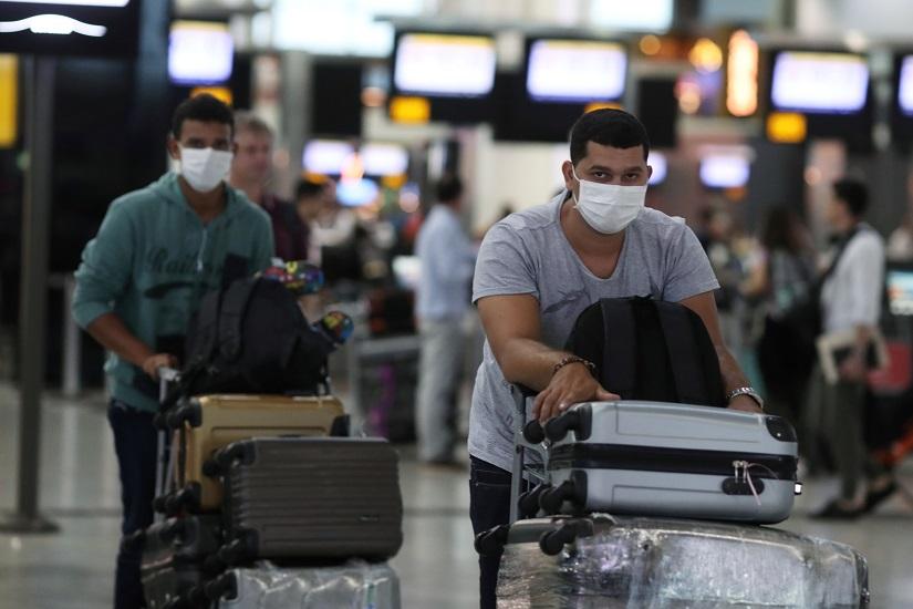 Travellers, wearing masks as a precautionary measure to avoid contracting coronavirus, are seen at Guarulhos International Airport in Guarulhos, Sao Paulo state, Brazil, Feb 3, 2020. REUTERS