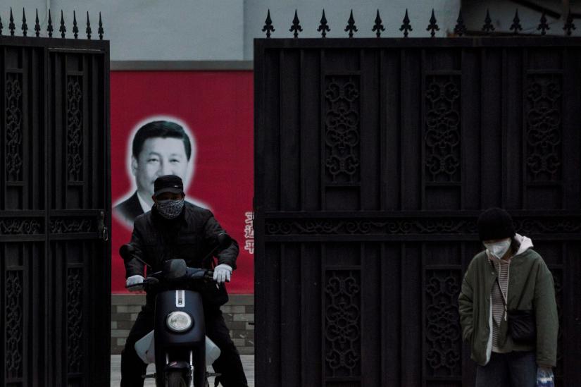 People wearing masks are seen in front of a portrait of Chinese President Xi Jinping on a street as the country is hit by an outbreak of the novel coronavirus, in Shanghai, China, February 10, 2020. REUTERS
