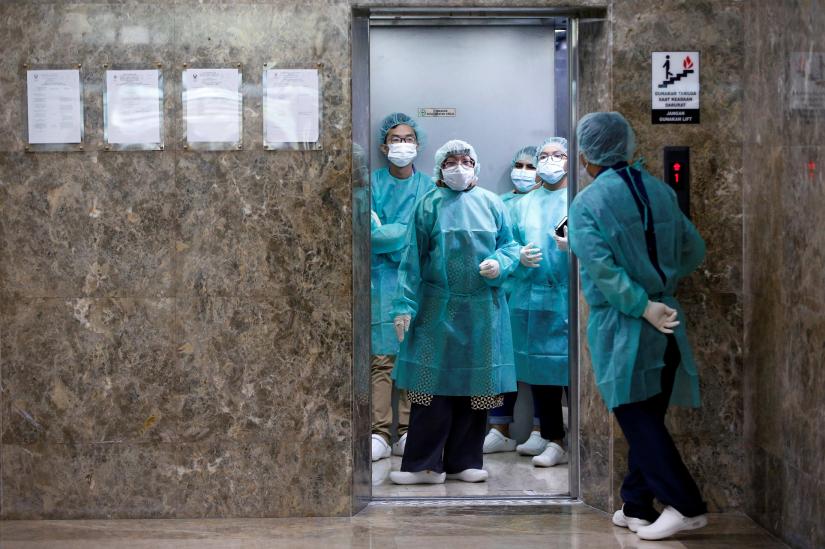 Journalists wear protective suits inside an elevator as they prepare for a media visit to Indonesian Health Ministry`s Laboratorium for Research on Infectious-Diseases, following the outbreak of the new coronavirus in China, in Jakarta, Indonesia, February 11, 2020. REUTERS