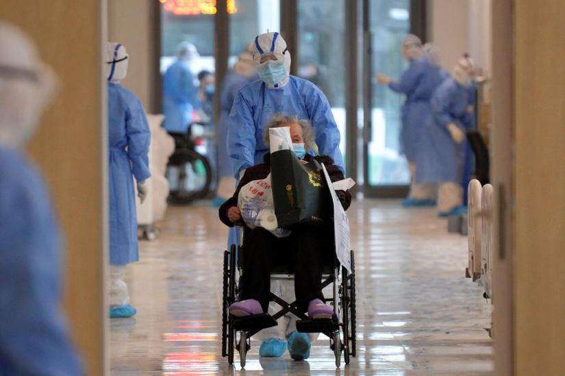 A medical worker in protective suit moves a novel coronavirus patient in a wheelchair at a hospital in Wuhan, Hubei province, China Feb 10, 2020. China Daily via REUTERS