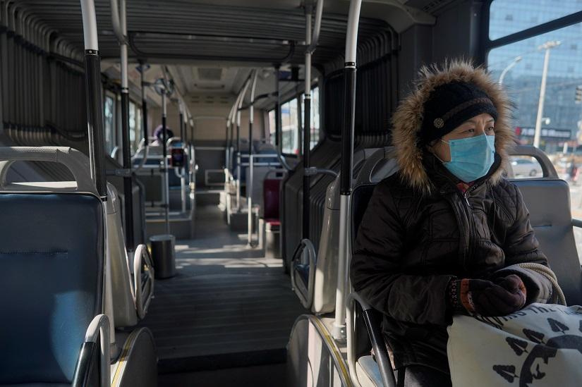 A woman wearing a face mask sits inside a public bus, as the country is hit by an outbreak of the novel coronavirus, in Beijing, China Feb 15, 2020. REUTERS