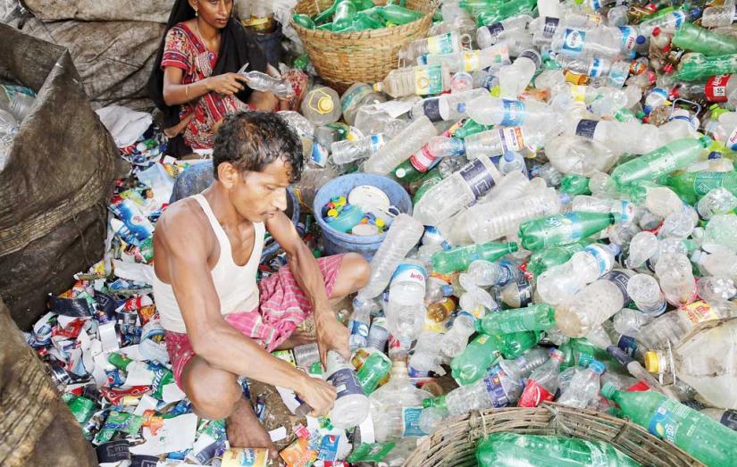 A man and a woman sorts out plastic bottles after they are collected from roadsides and garbage bins. File Photo/Syed Zakir Hossain