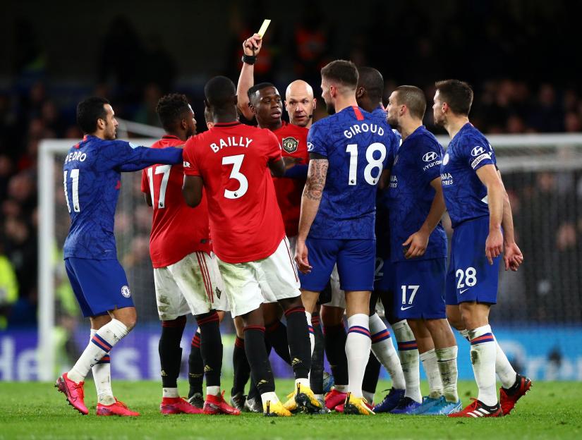 Premier League - Chelsea v Manchester United - Stamford Bridge, London, Britain - February 17, 2020 Manchester United`s Aaron Wan-Bissaka is shown a yellow card by referee Anthony Taylor as Chelsea`s Mateo Kovacic, Cesar Azpilicueta and teammates react REUTERS