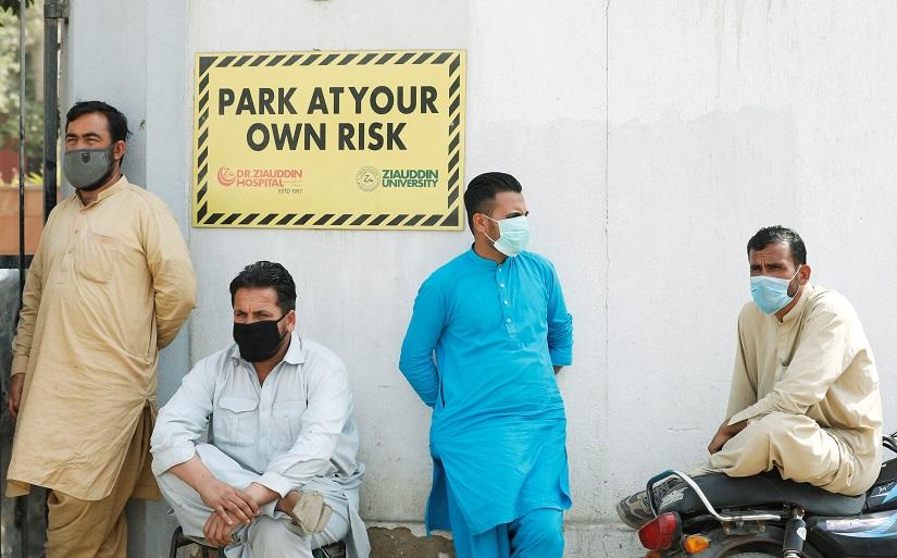 FILE PHOTO: Men wearing face masks wait to see their relatives who were admitted after being affected from a suspected gas leak, at the hospital entrance in Karachi, Pakistan Feb 18, 2020. REUTERS