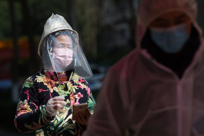 A resident wearing makeshift protective face shield waits to collect food and necessities purchased through group orders at an entrance to a residential compound in Wuhan, the epicentre of the novel coronavirus outbreak, Hubei province, China February 21, 2020. REUTERS