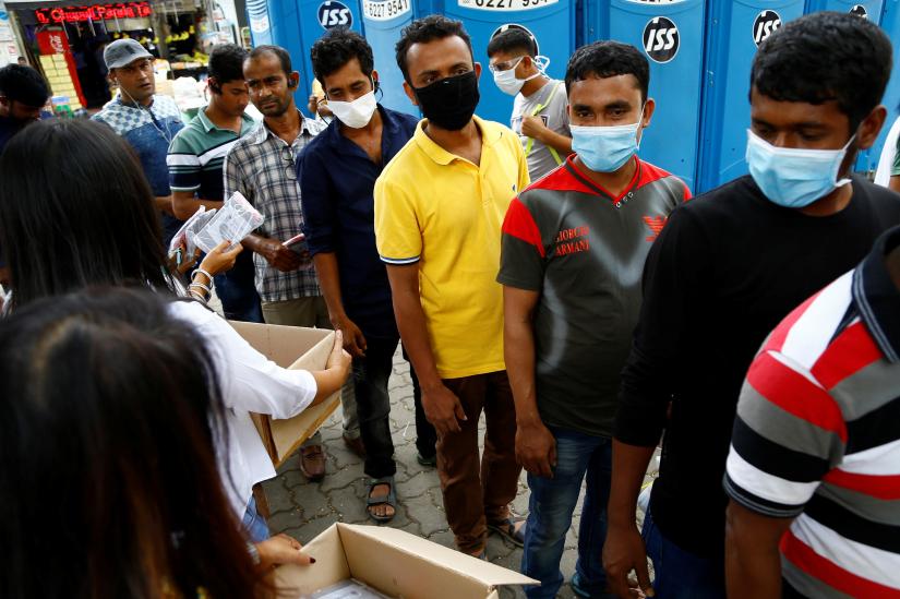 Migrant workers mostly from Bangladesh queue to collect free masks and have their temperatures checked in Singapore on Feb 23, 2020. REUTERS