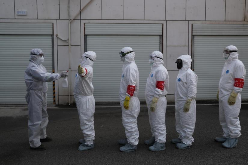 Volunteers in protective suits are being disinfected in a line in Wuhan, the epicentre of the novel coronavirus outbreak, in Hubei province, China Feb 22, 2020. China Daily via REUTERS