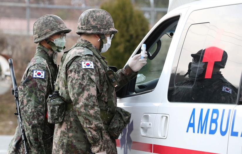 South Korean soldiers wearing masks to prevent contacting the coronavirus stand guard at a checkpoint of a military base in Daegu, South Korea, February 26, 2020. Yonhap via REUTERS