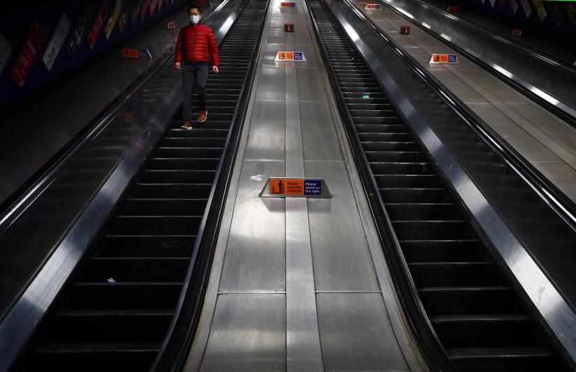 A man wearing a protective face mask on escalators inside London Bridge underground station as the spread of the coronavirus disease (COVID-19) continues, in London, Britain, March 18, 2020. REUTERS
