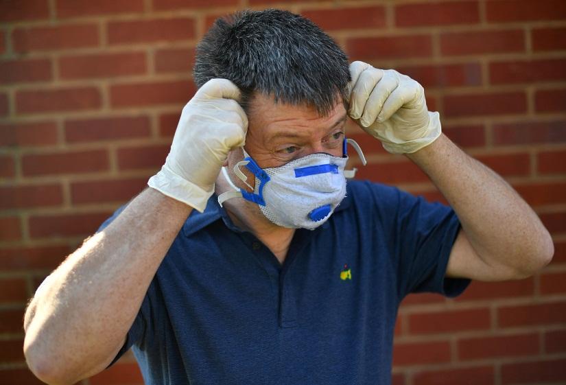 Niall Barrett puts on a mask outside Guy`s and St Thomas` Hospital after dropping off food as the spread of the coronavirus disease (COVID-19) continues, in London, Britain, Mar 23, 2020. REUTERS