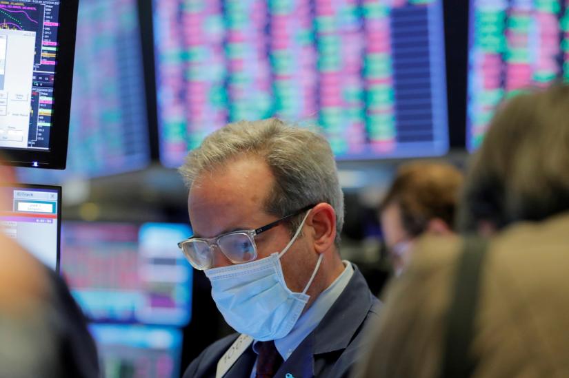 FILE PHOTO: A trader wears a mask as he works on the floor of the New York Stock Exchange (NYSE) as the building prepares to close indefinitely due to the coronavirus disease (COVID-19) outbreak in New York, U.S., March 20, 2020. REUTERS