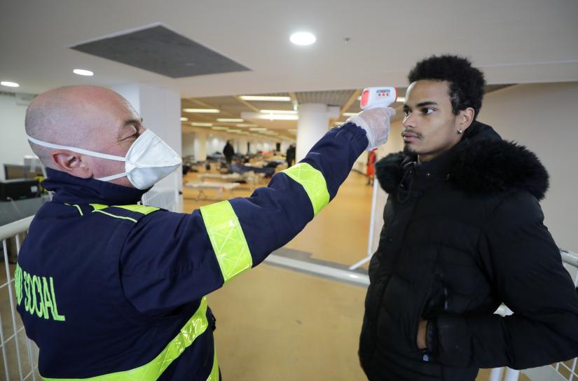 A member of the SAMU, the emergency service for homeless people, checks the body temperature of Jean Paul inside the Festival palace as Cannes Mayor David Lisnard decided to open a part of the palace to welcome needy and homeless as a lockdown is imposed to slow the rate of the coronavirus disease (COVID-19) in France, March 24, 2020. REUTERS/