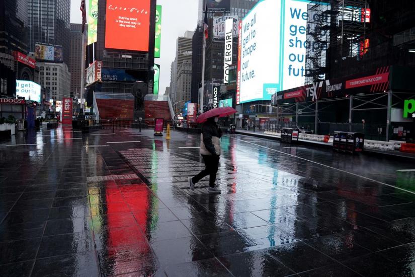 FILE PHOTO: A lone person walks in the rain in a mostly deserted Times Square following the outbreak of Coronavirus disease (COVID-19), in the Manhattan borough of New York City, New York, US, Mar 23, 2020. REUTERS