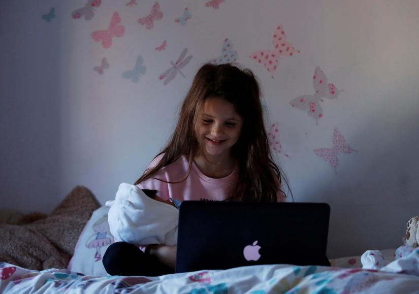 Milly aged 7 talks with her friend on a video call in her home while the spread of the coronavirus disease (COVID-19) continues, in Hertford, Britain, March 26, 2020. REUTERS