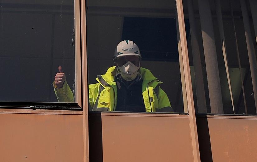 A construction worker gestures from inside a building as the spread of the coronavirus disease (COVID-19) continues, in Northwich, Britain, Mar 27, 2020. REUTERS