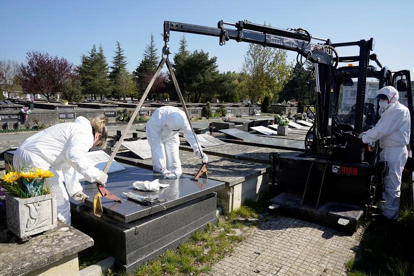 Municipal workers wearing protective gear seal the niche of a coronavirus disease (COVID-19) victim at El Salvador cemetery in Vitoria, Spain, Mar 27, 2020. REUTERS