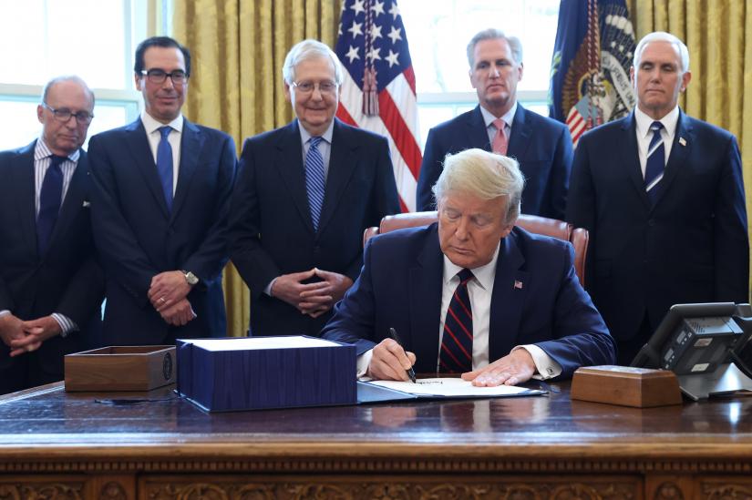 U.S. President Donald Trump signs the $2.2 trillion coronavirus aid package bill as Treasury Secretary Steven Mnuchin, Senate Majority Leader Mitch McConnell (R-KY), House Minority Leader Kevin McCarthy (R-CA) and Vice President Mike Pence stand by during a signing ceremony in the Oval Office of the White House in Washington, U.S., March 27, 2020. REUTERS