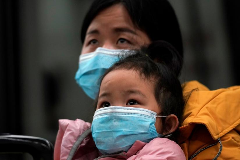 A woman wearing a face mask holds a child as they arrive at a railway station in Wuhan on the first day inbound train services resumed following the novel coronavirus disease (COVID-19) outbreak, in Wuhan of Hubei province, the epicentre of China`s coronavirus outbreak, March 28, 2020. REUTERS