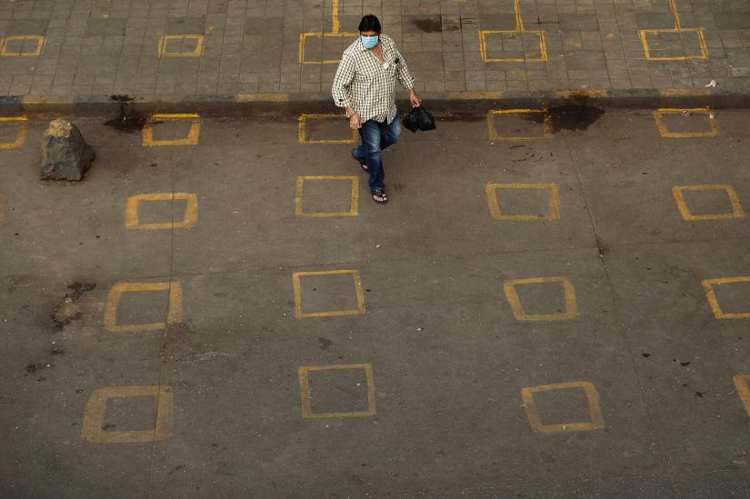 A man wearing a protective mask walks on a street with squares painted on it for maintaining safe distance, to limit the spread of the coronavirus disease (COVID-19) in Mumbai, India March 28, 2020. REUTERS