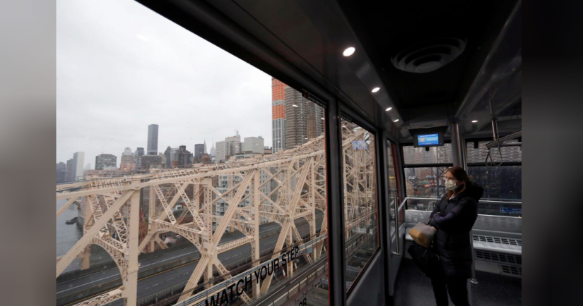 A woman in a face mask looks over an empty Queensboro Bridge while riding The Roosevelt Island Tramway from Manhattan during the outbreak of the coronavirus disease (COVID-19) in New York City, U.S., March 28, 2020. Picture taken March 28, 2020. REUTERS