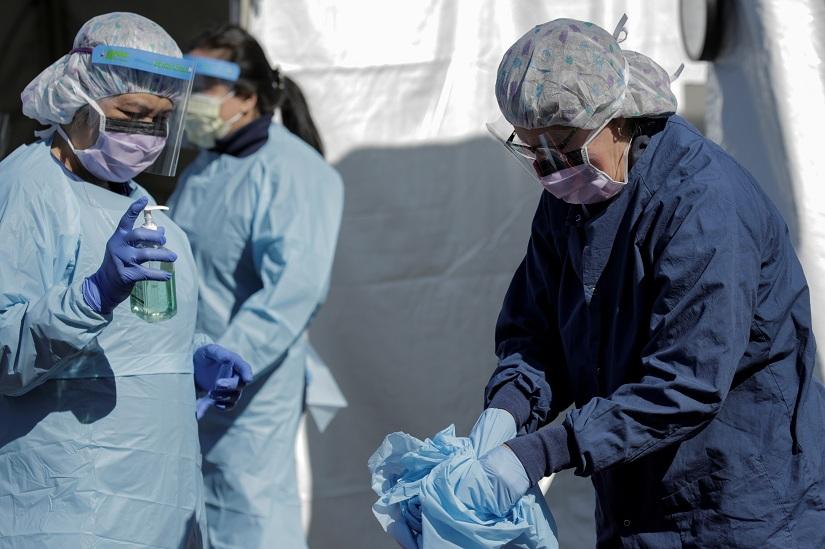 A nurse changes her personal protective equipment after administering a test for coronavirus disease (COVID-19) to a patient at a drive-through testing site in a parking lot at the University of Washington`s Northwest Outpatient Medical Center, during the coronavirus disease (COVID-19) outbreak, in Seattle, Washington, US Mar 18, 2020. REUTERS