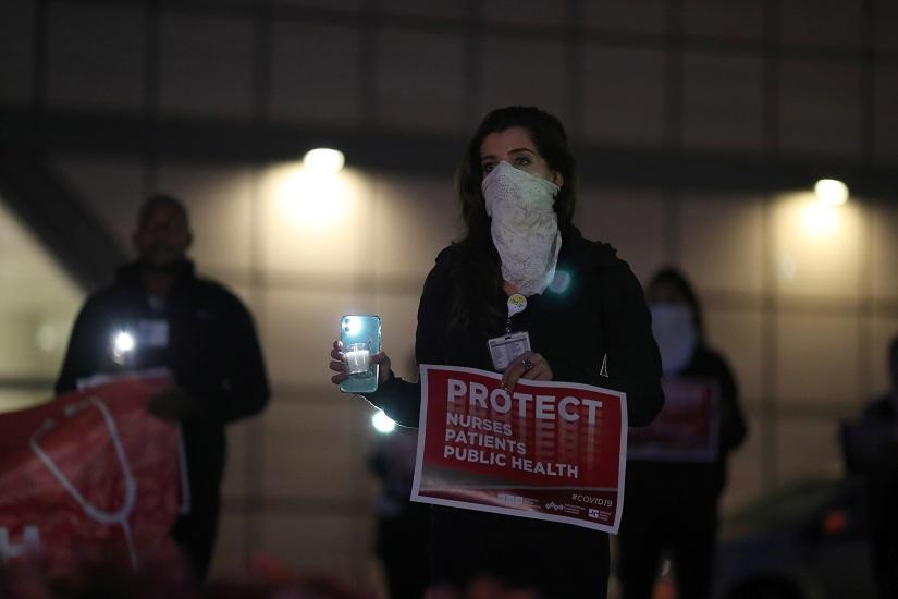 A nurse takes part in a candlelight vigil outside UCLA Ronald Reagan Medical Center to `show solidarity and support for nurses across the nation and to demand stronger leadership from the federal government in protecting the health and safety of all healthcare workers and their patients`, according to event organizers, during the global outbreak of coronavirus disease (COVID-19), in Los Angeles, California, US, Mar 30, 2020. REUTERS